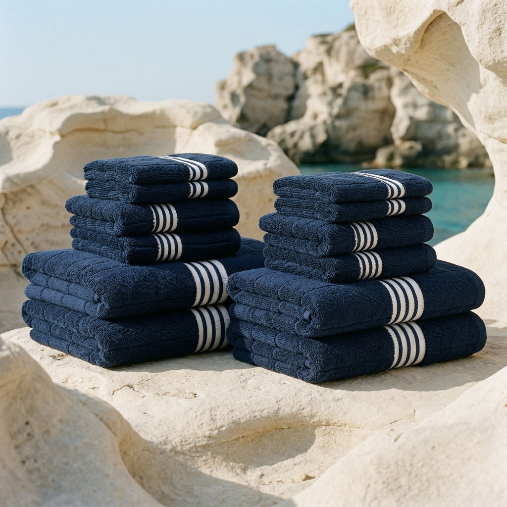 Pair stacks of navy cotton towels with white stripe bands arranged on rocks.
