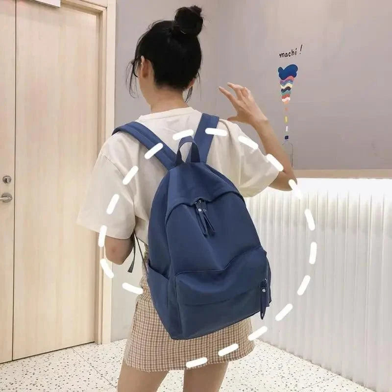 Blue mini backpack with drawstring closure and front pocket, worn on shoulder
