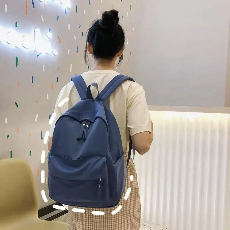 Navy-blue backpack with front pocket and adjustable straps on a person