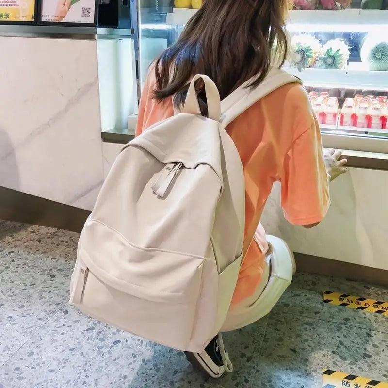 Cream canvas backpack with front pocket and adjustable shoulder straps