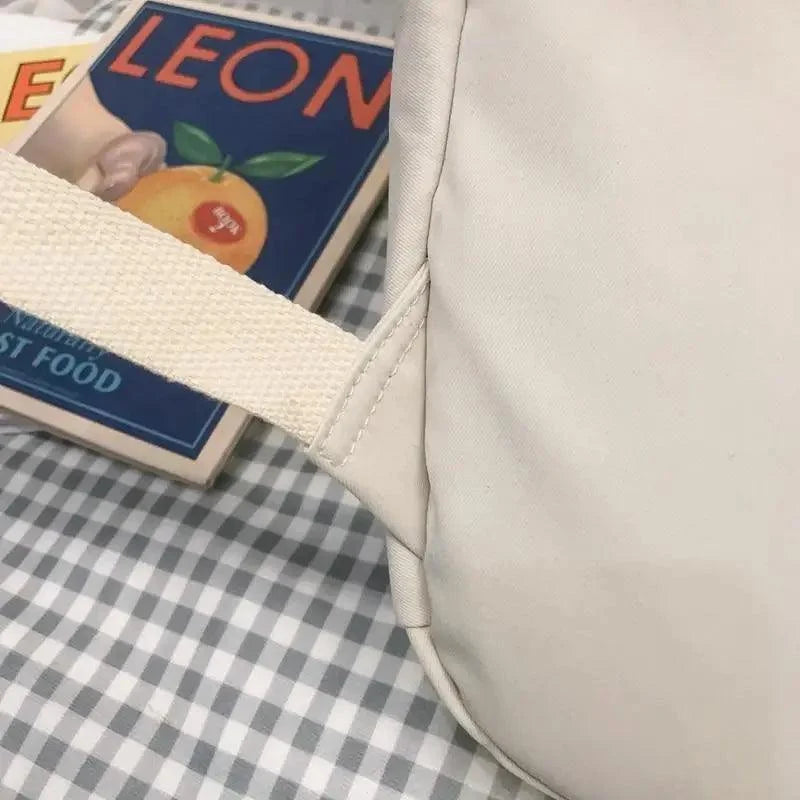 Light beige backpack corner with stitching, side loop, and interior edge