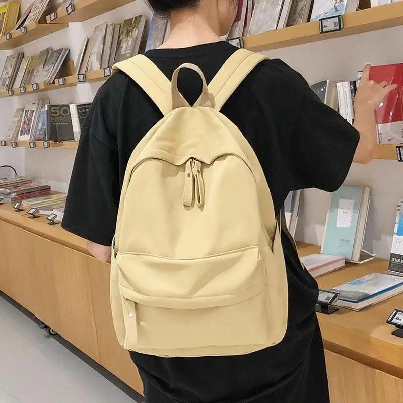 Light yellow mini backpack with front pocket and adjustable straps, worn