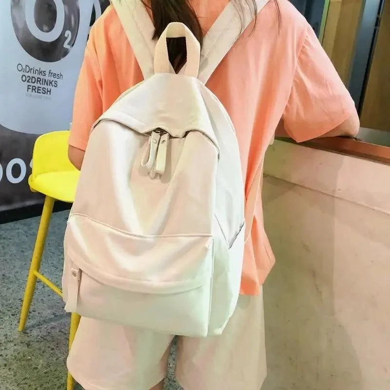 Cream backpack with drawstring top and front zip pocket, worn on back