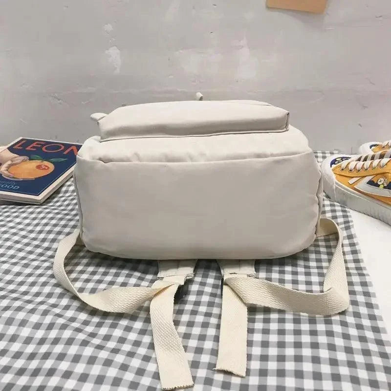 Cream backpack with wide top flap and two front straps