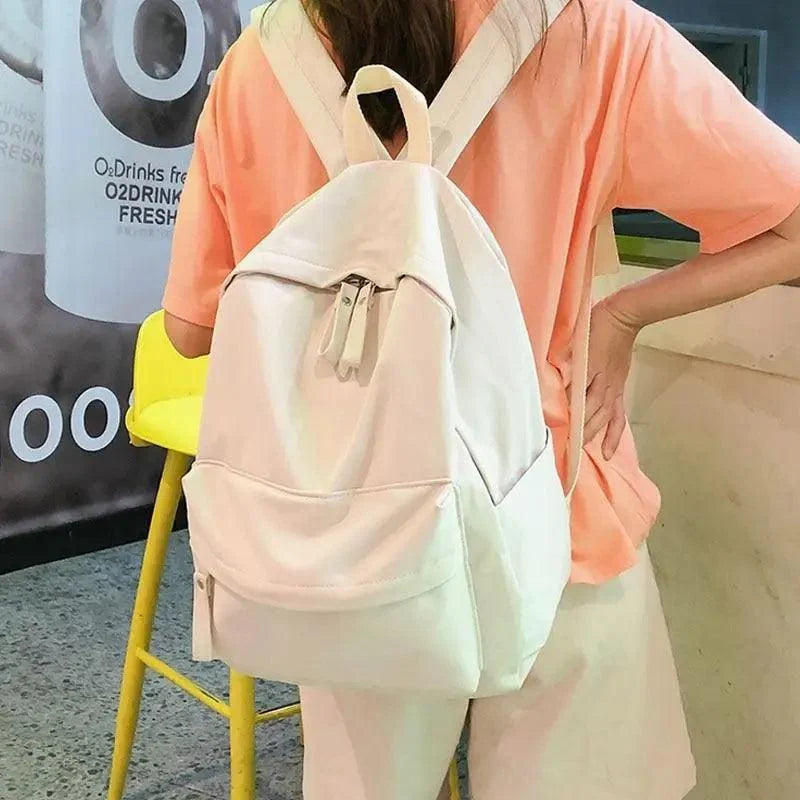 Cream backpack with drawstring top cord, front pocket, and adjustable shoulder straps