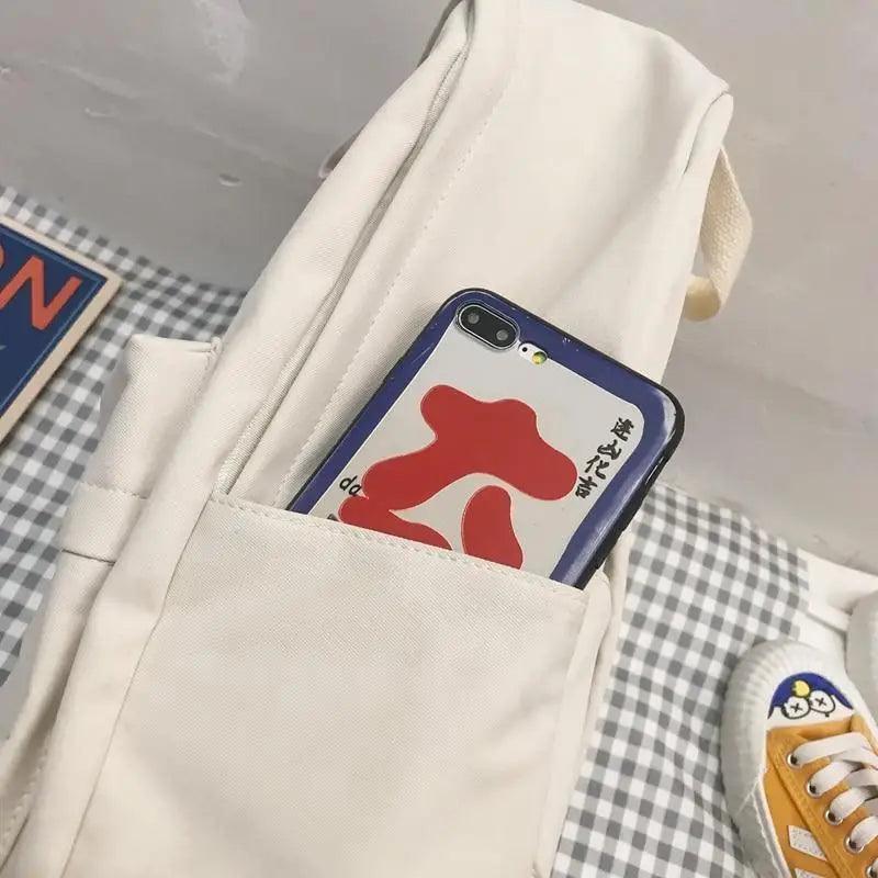 Cream canvas backpack with inner sleeve holding a smartphone, front view
