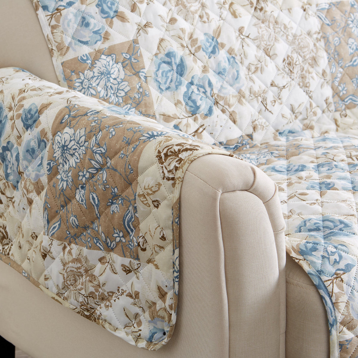 Reversible floral patchwork sofa protector draped on armrest, blue floral quilt