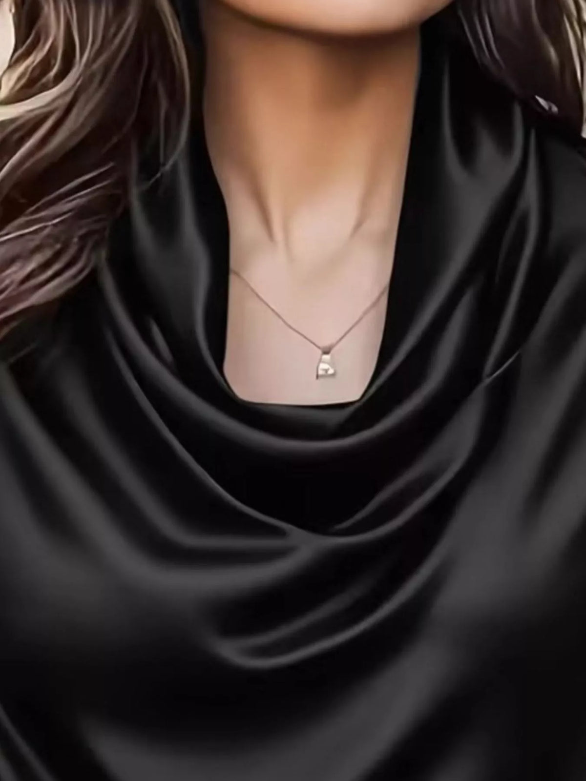 Black satin cowl-neck blouse close-up with draped neckline