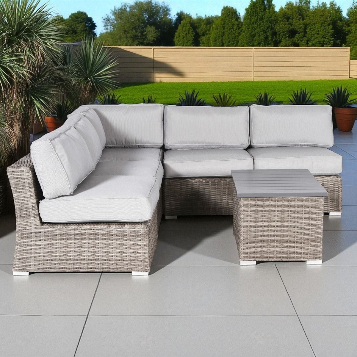 Wicker sectional sofa with white seat cushions and light gray woven side table
