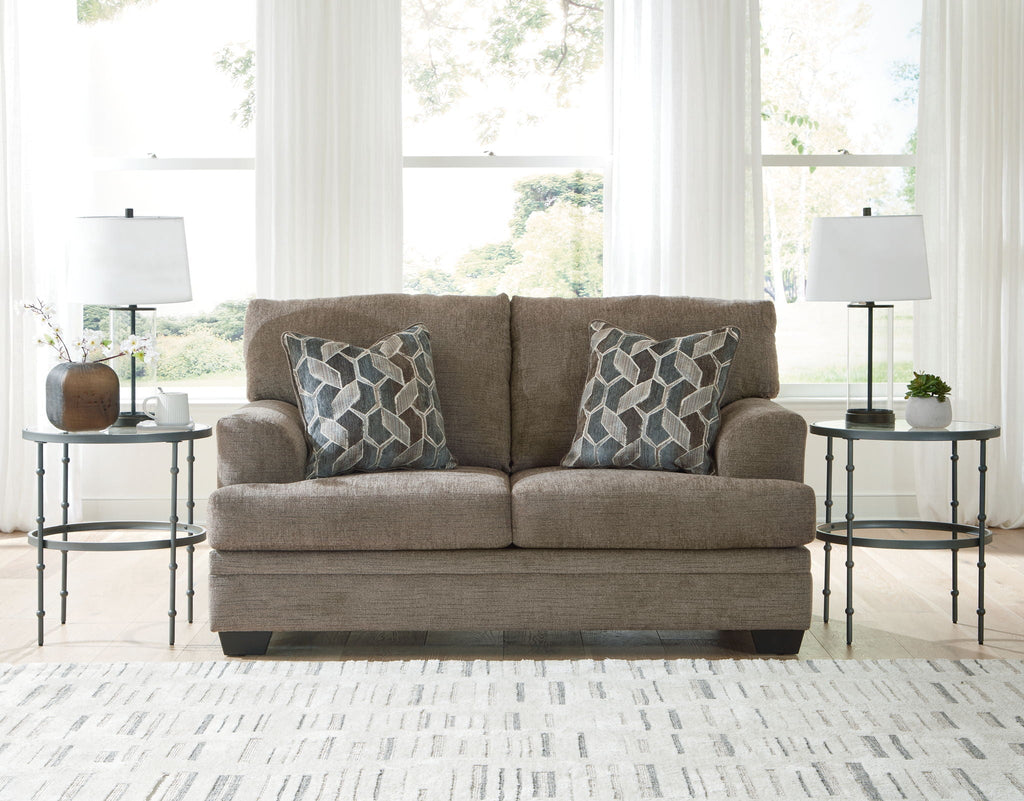 Upholstered loveseat in heather gray fabric with two geometric accent pillows and tall back