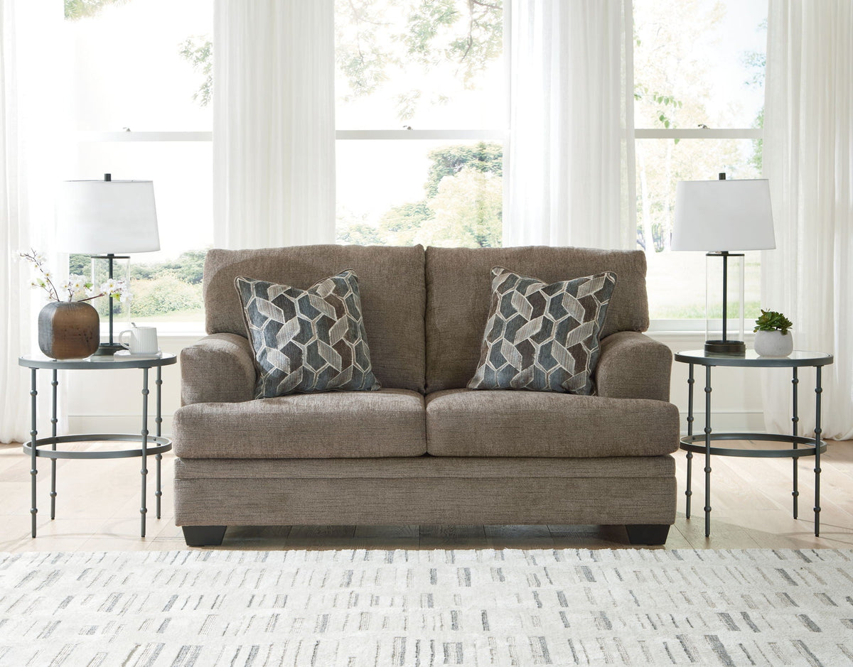 Upholstered loveseat in heather gray fabric with two geometric accent pillows and tall back
