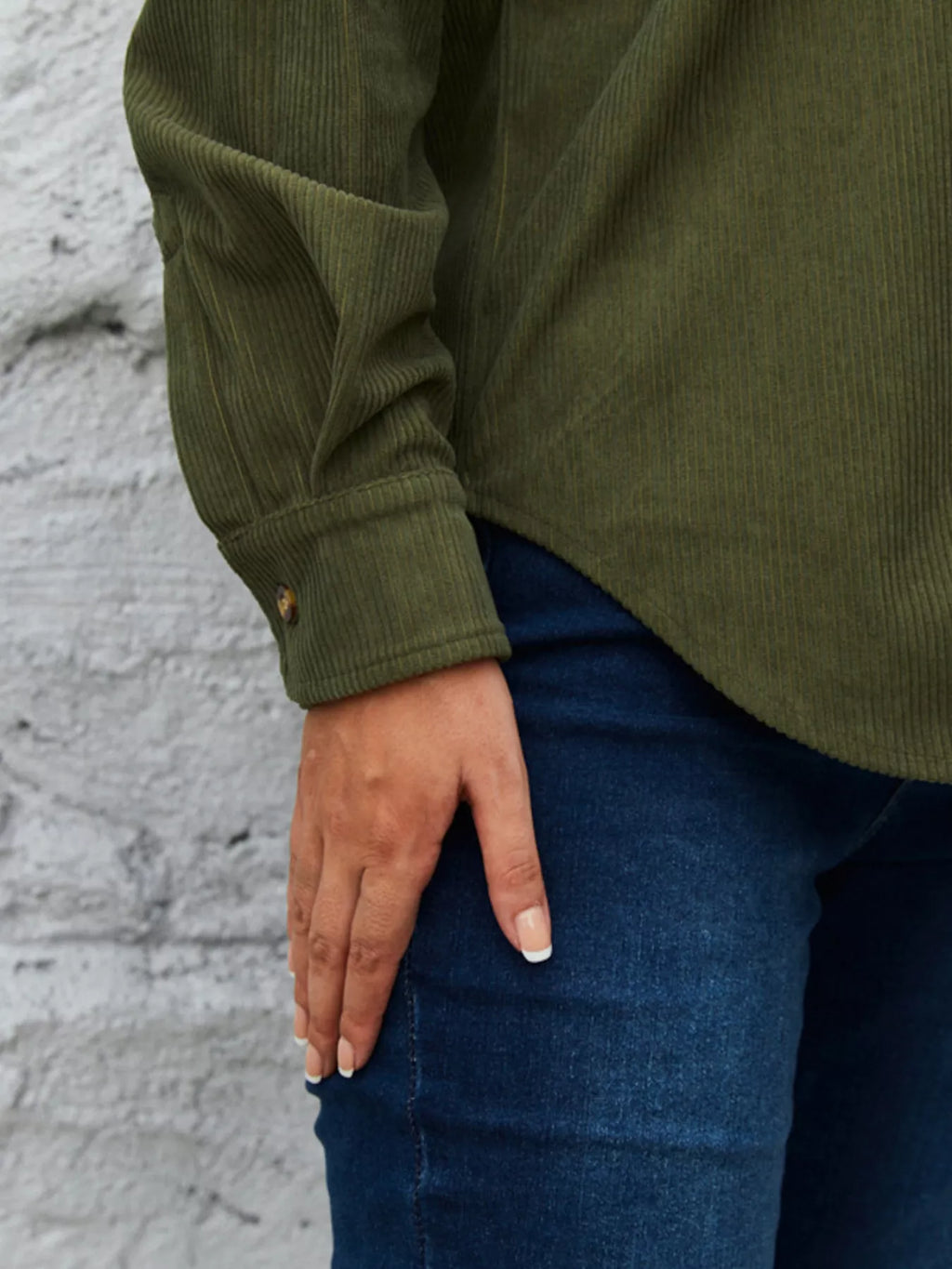 Olive corduroy button-front shirt sleeve detail with button cuff and blue jeans