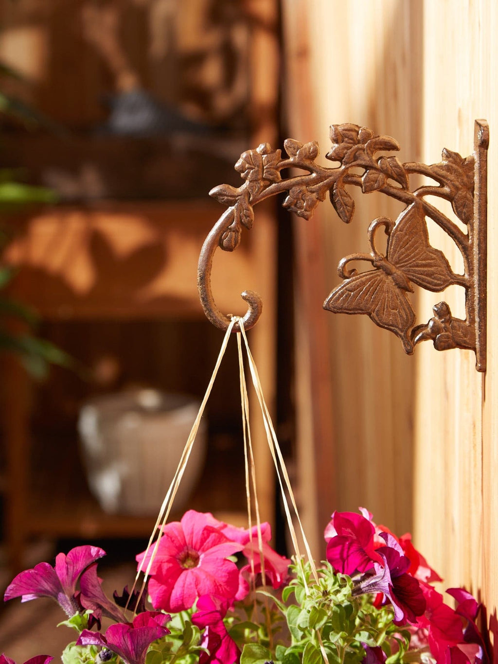 Cast iron planter bracket close-up with butterfly relief and hanging pot below