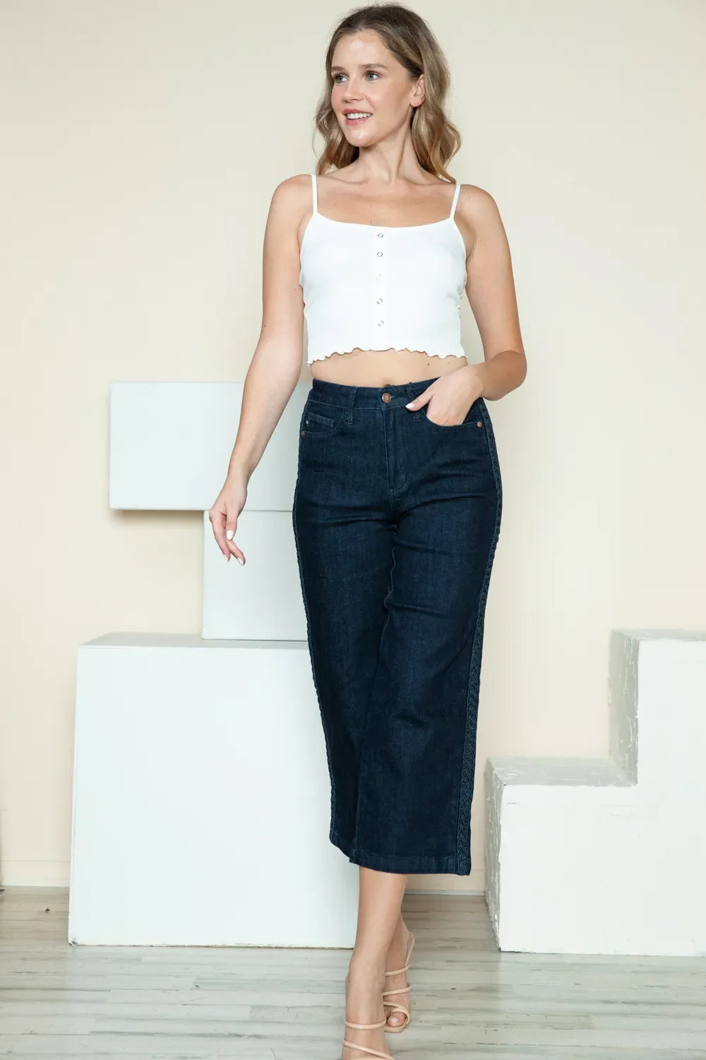 Dark wide-leg cropped jeans with side braid detail, three-quarter front view