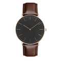 Quartz wristwatch with black dial, brown leather strap, gold-toned case