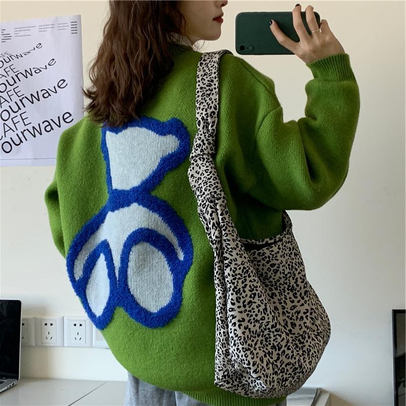 Women’s green knit sweater close-up of blue heart and arrow graphic