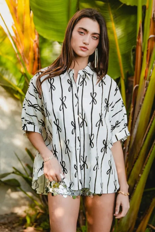 Off-white button-down shirt with short sleeves, black cactus-like print, and front buttons
