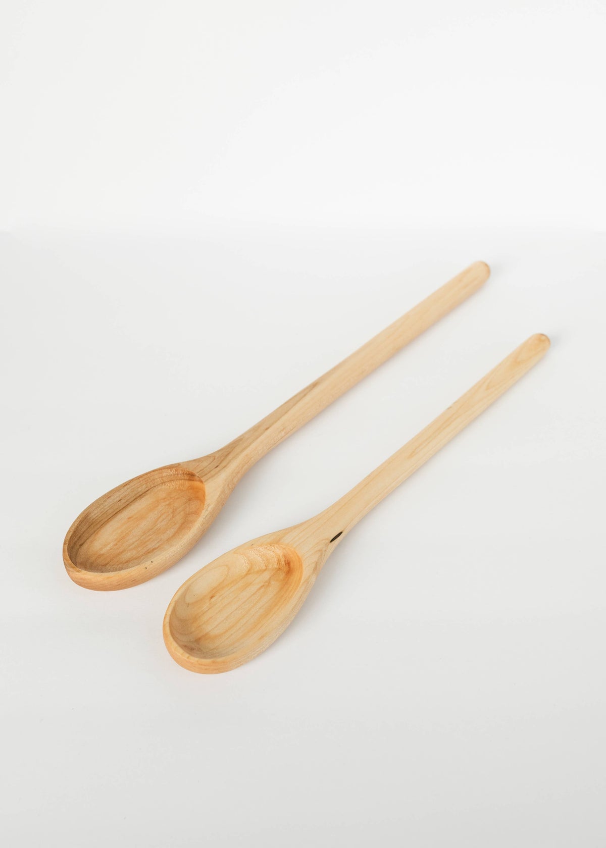 Two light wood spoons with oval bowls and slim long handles.