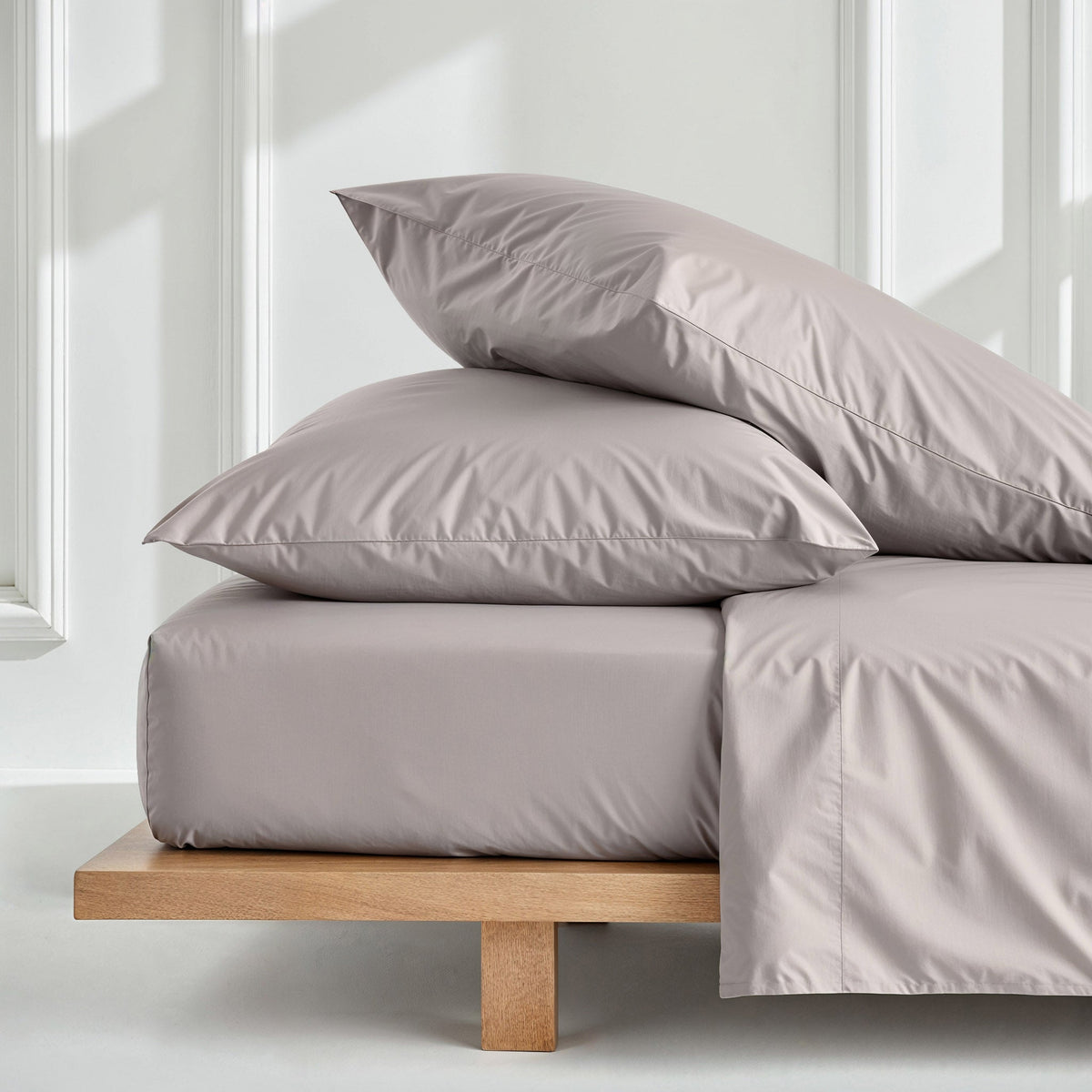 Light gray sateen bedding bundle with pillows and folded duvet