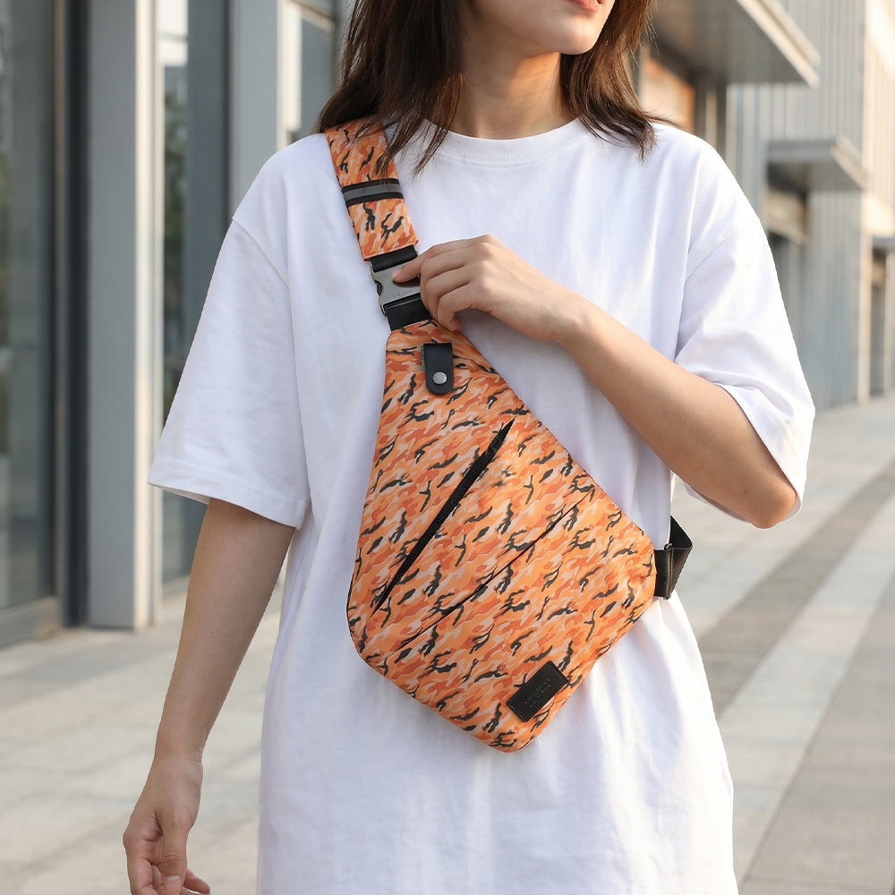 Orange camouflage crossbody bag on shoulder with black strap over white T-shirt
