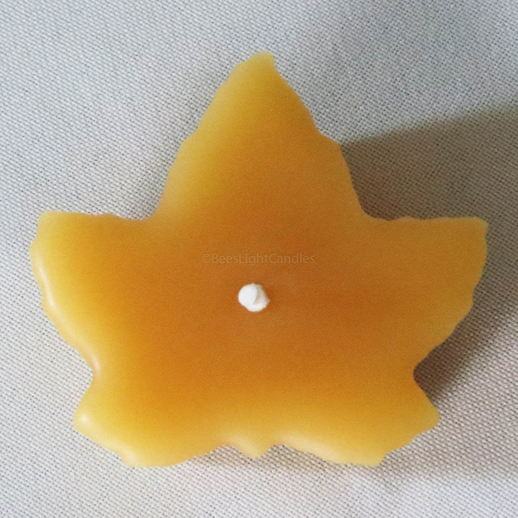 Yellow maple leaf beeswax candle with centered melt pool and unlit wick