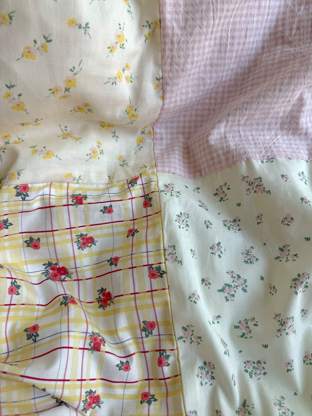 Close-up of pastel floral duvet fabric with light background, gingham, and small flowers
