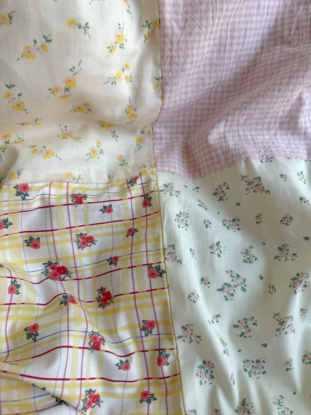 Close-up of pastel floral duvet fabric with light background, gingham, and small flowers