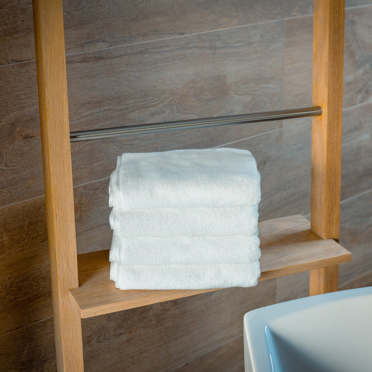 Light blue bath mats folded and stacked on a wooden bench