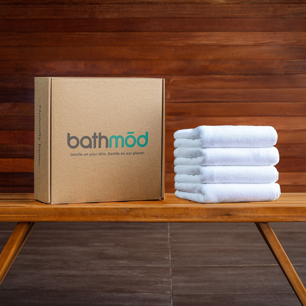 Light blue bath mat stack beside a bath mat four-pack box