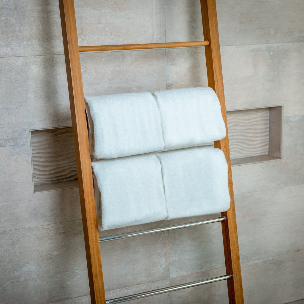 White bath towel set folded on a metal ladder shelf