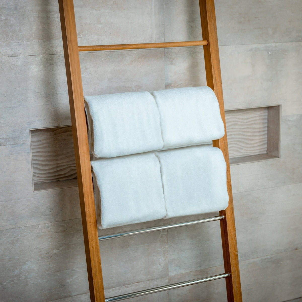 White bath towel set folded on a metal ladder shelf