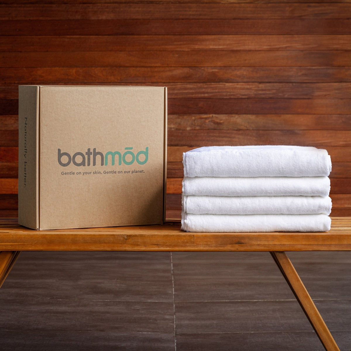 Organic bath towel four-pack, folded white towels beside branded box