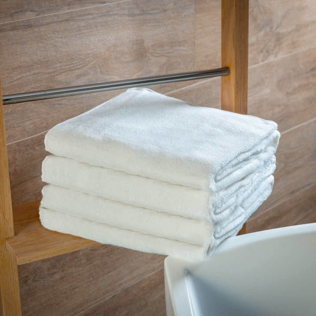 Stack of folded white bath towels on a wooden bench