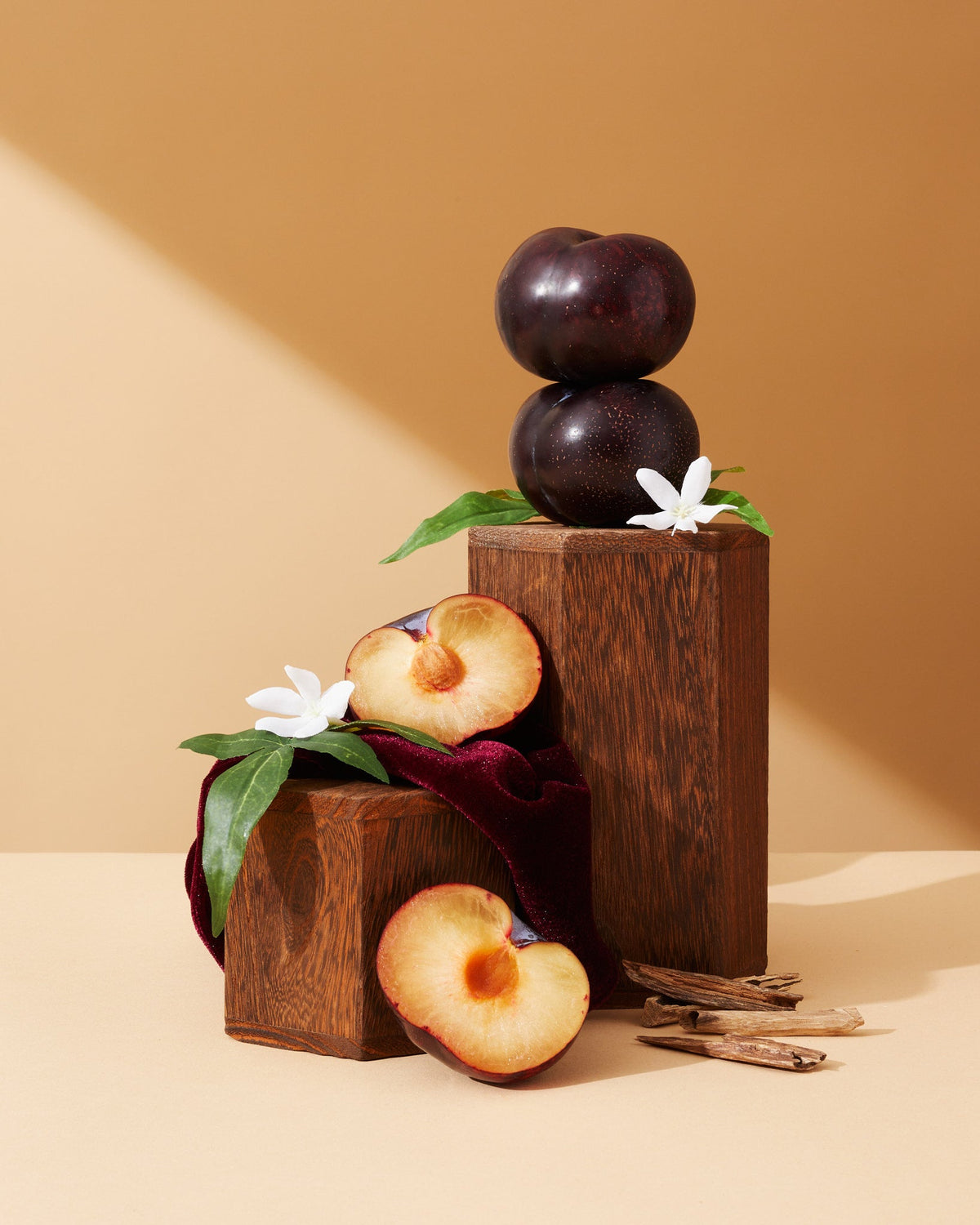 Damask plum & velvet cashmere™ fragrance oil with dark wooden display and white blossoms
