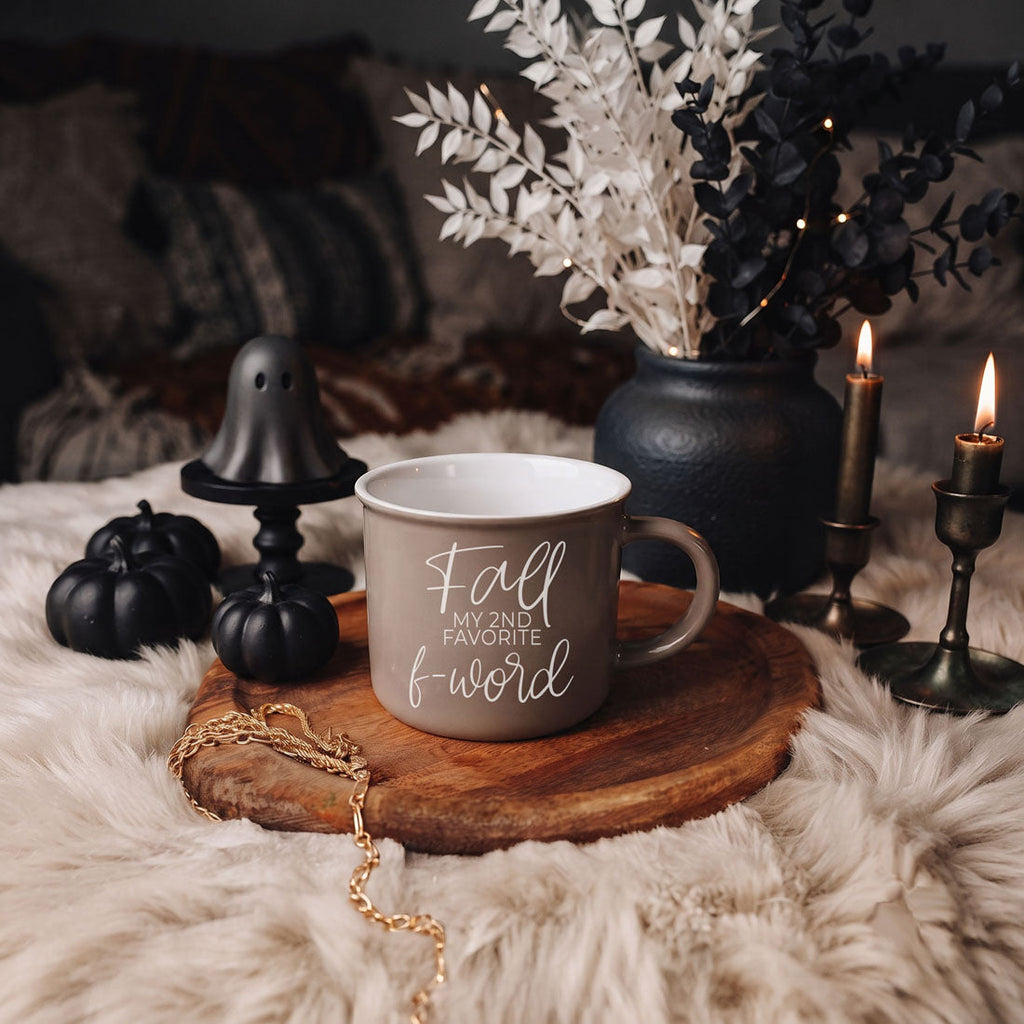 Beige mug with white lettering on a wooden slice, surrounded by fall decor