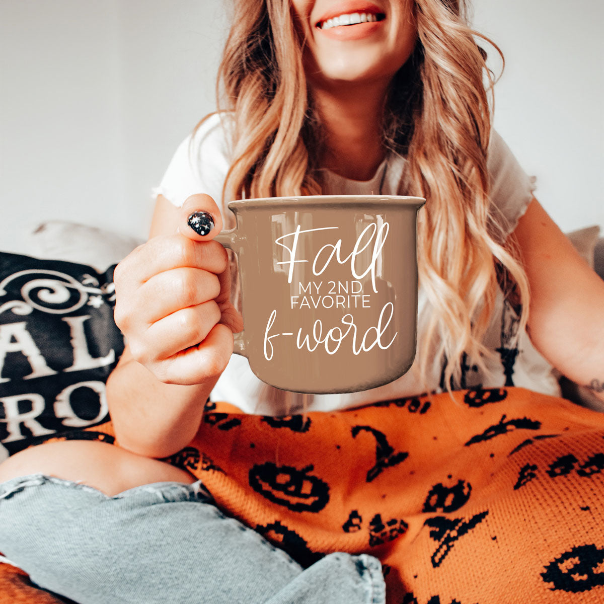 Brown ceramic coffee mug with white “fall” and “f-word” lettering, held by person