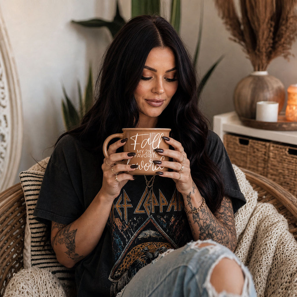 Woman holding beige mug with white script quote, seated on a couch