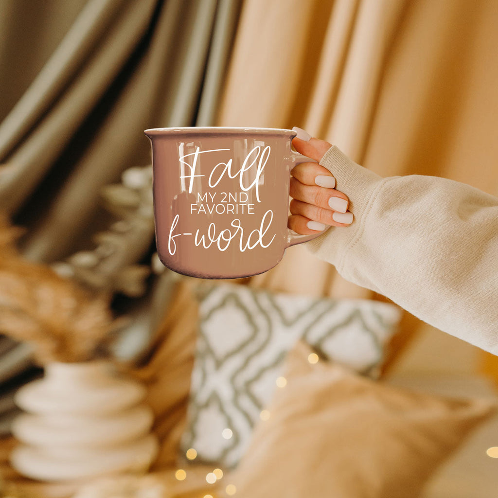 Taupe mug held in a hand with white 'Fall' lettering and handle