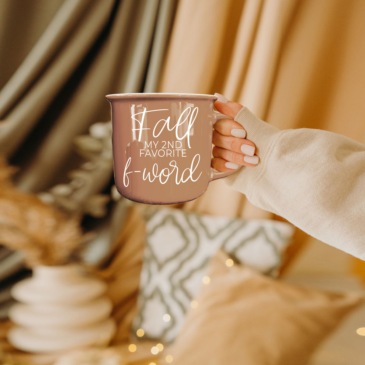 Taupe mug held in a hand with white 'Fall' lettering and handle