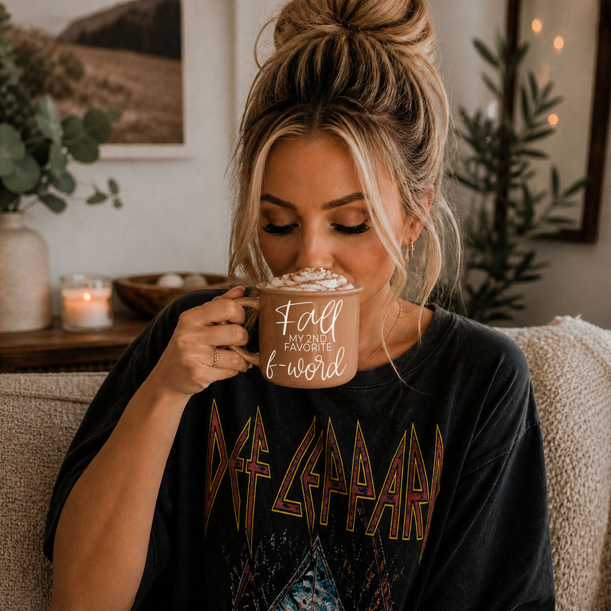 Beige ceramic mug with white script quote, held near lips by a seated woman