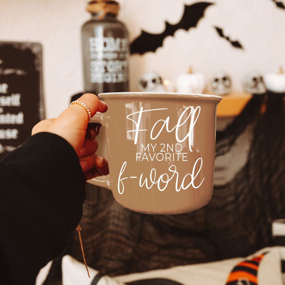Hand holding beige mug with white script quote printed on the front