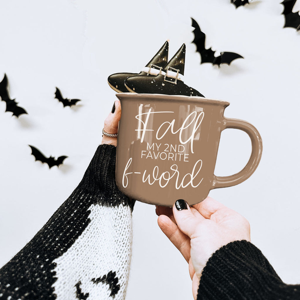 Taupe ceramic mug with white 'Fall' quote held in one hand