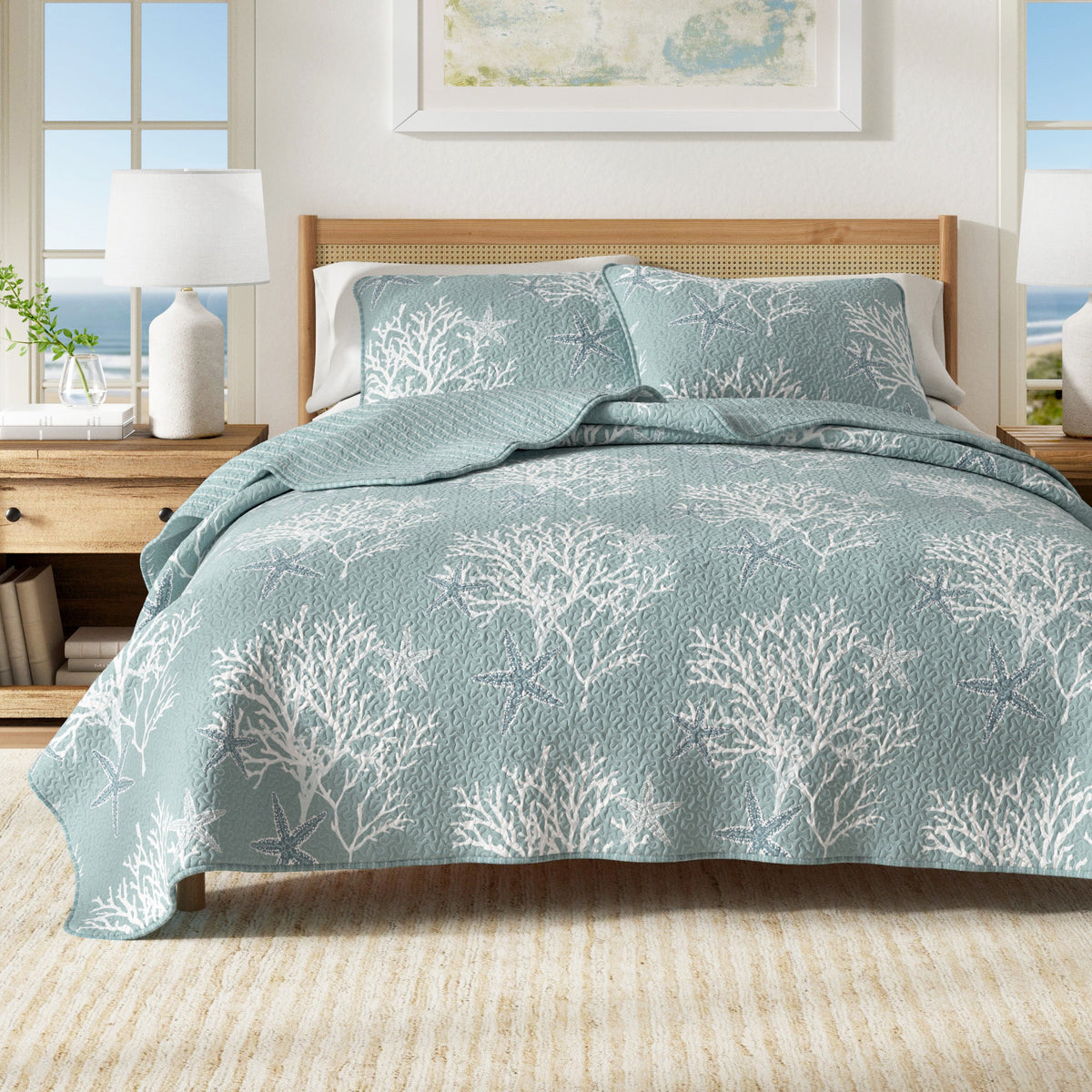 Blue quilt set on bed with starfish and coral pattern, plus two matching pillow shams.