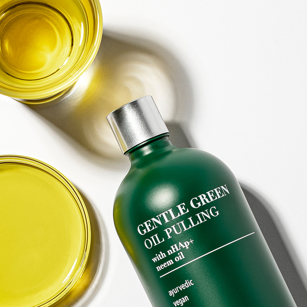 Gentle green oil pulling rinse bottle beside golden oil jars