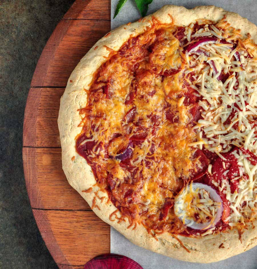 Baked gluten-free pizza on wooden board, with melted cheese and red sauce