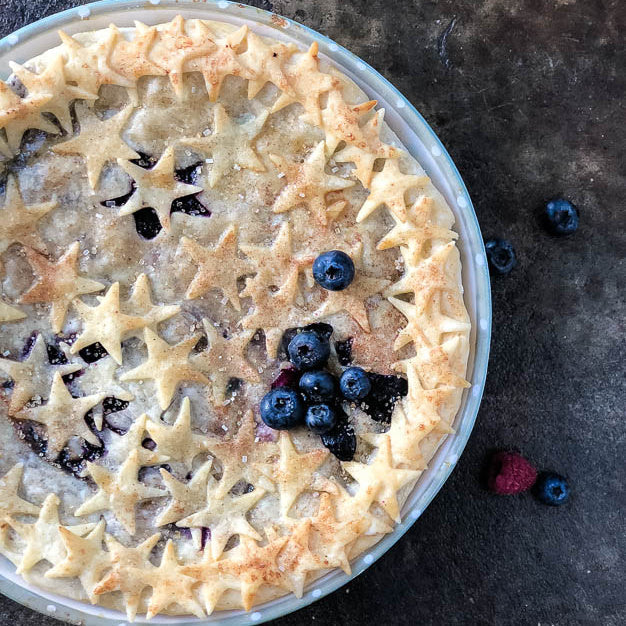 Gluten-free flour fruit pie with star cutout crust and scattered berries.