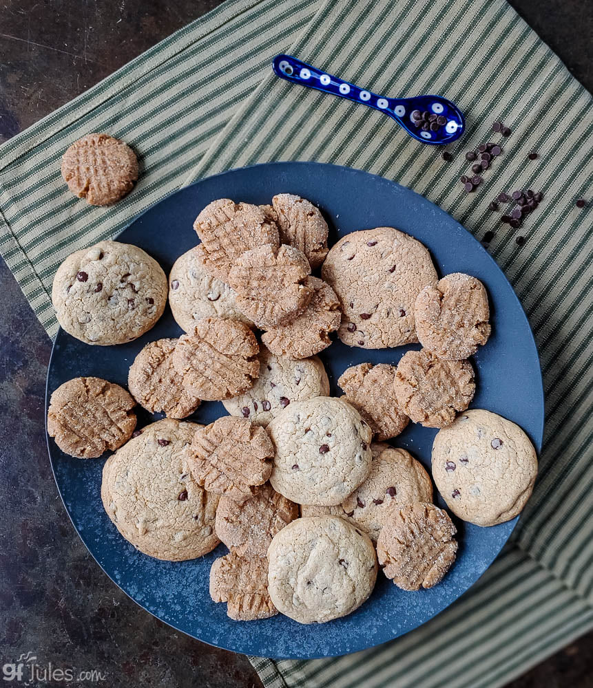 Gluten-free flour cookies on a blue plate with a small cookie scoop and crumbs