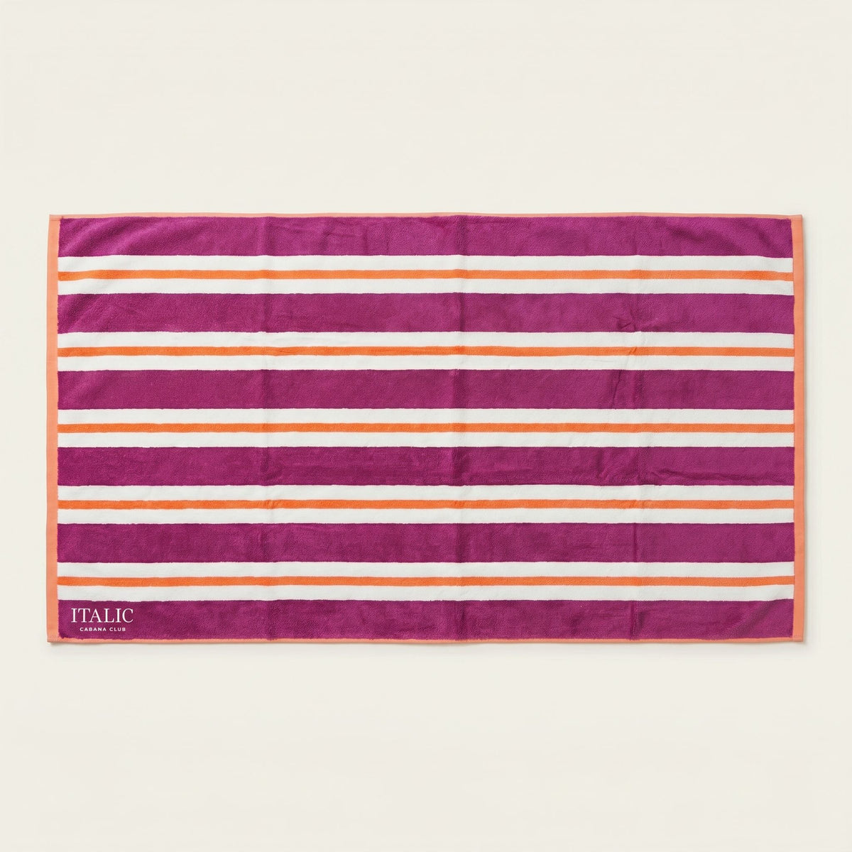 Cotton beach towel with magenta and orange striped bands and “ITALIC” label