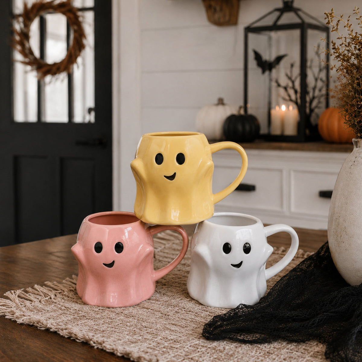 Set of ghost-shaped mugs in yellow, pink, and white with smiling faces