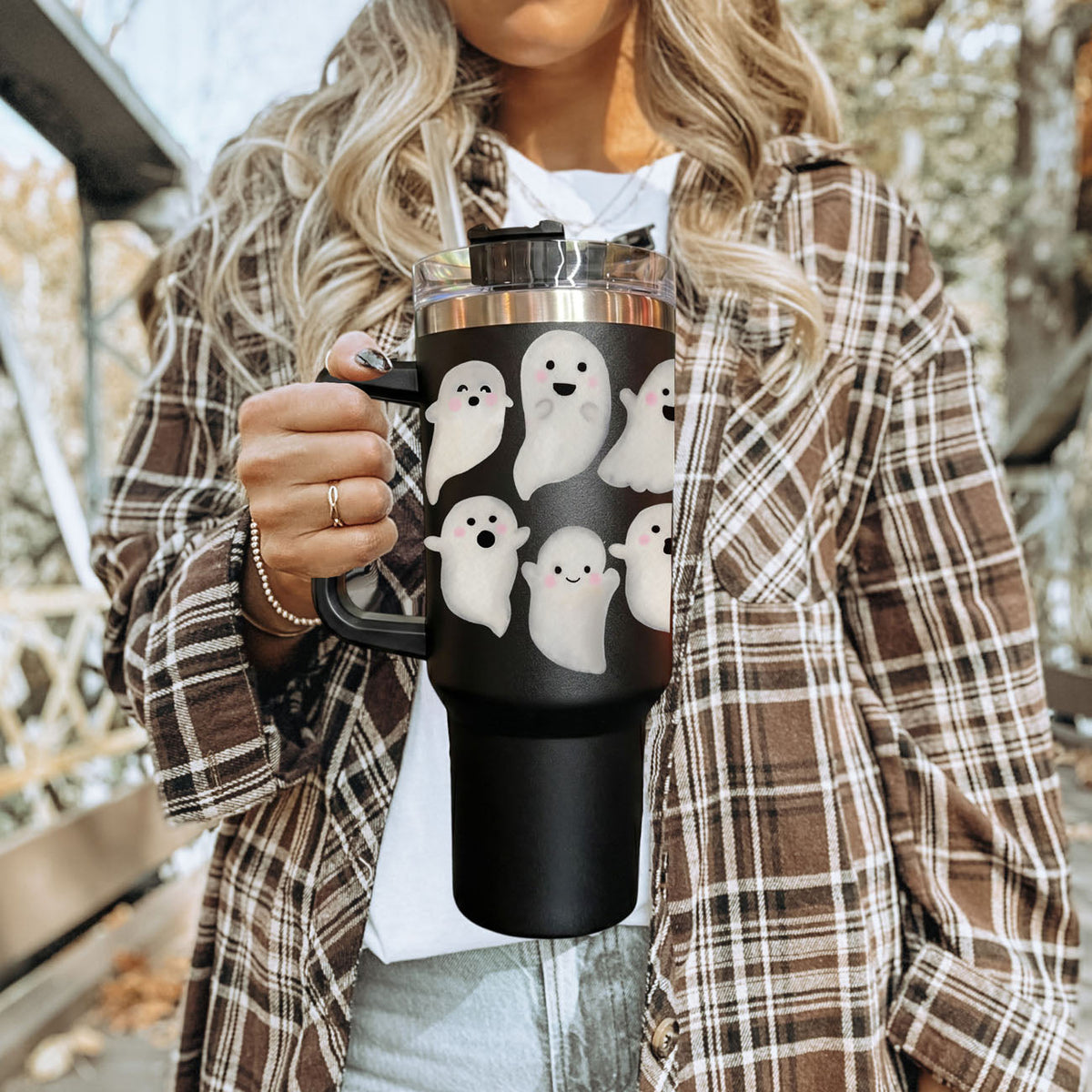 Black 40oz tumbler with white ghost design, clear lid, straw, held outdoors